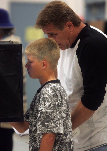 Austin Hentsch, 11, helps his father, George, vote Tuesday at Elton M. Garrett Middle School in Boulder City.