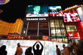 A man takes a photo as pedestrians on the Las Vegas Strip stop outside the Planet Hollywood to watch television news coverage of Democratic President-Elect Barack Obama giving his acceptance speech Tuesday night. 