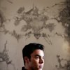 Artist Daniel Samaniego sits in front of his drawing 
