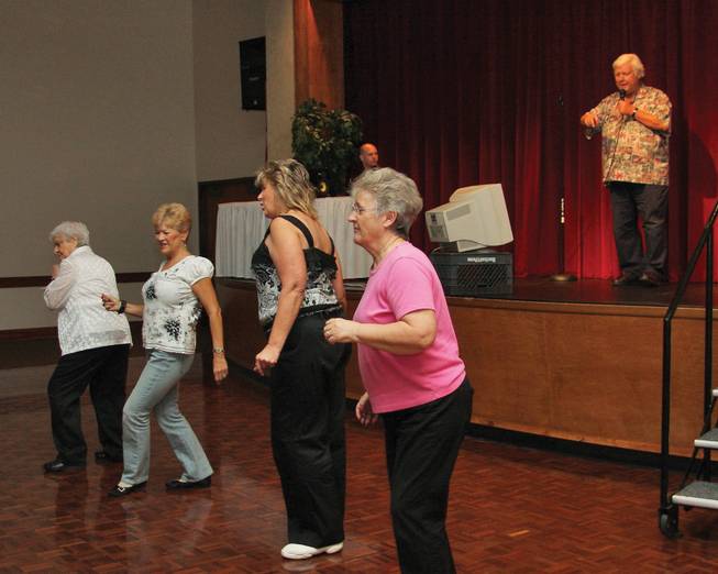 From left in the foreground, Marie Edens, Barbara Eubanks, Connie Herriman and Gillian Romesburg dance along with the singing of Bill Scarborough, in the background, as he sings "Elvira" by the Oak Ridge Boys during karaoke night at Sun City MacDonald Ranch.