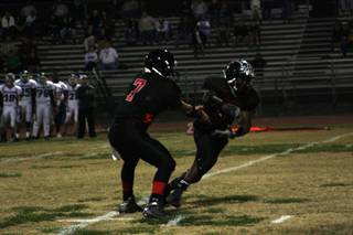 Las Vegas quarterback Emir Lopez (7) passes the ball off to Reggie Bullock (5) in the game against Green Valley Friday.