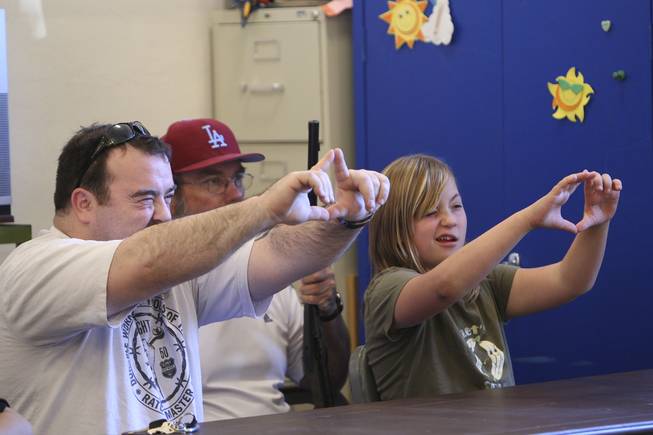 Abigail Harling, 9, gets a lesson on eye dominance from her dad, Tom, left, before competing in the annual Turkey Shoot Tuesday at the Boulder City Recreation Center.  Sitting behind holding her BB gun is parks and recreation employee Randy Shea.
 