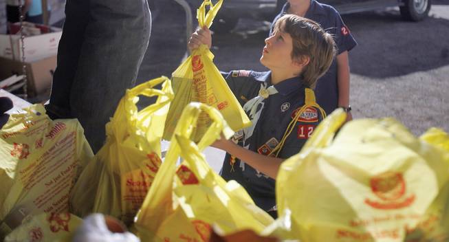 As part of the holiday food drive, Cub Scout Christian Long, hands off bags of donated food to be sorted at the Emergency Aid office in Boulder City on Saturday.