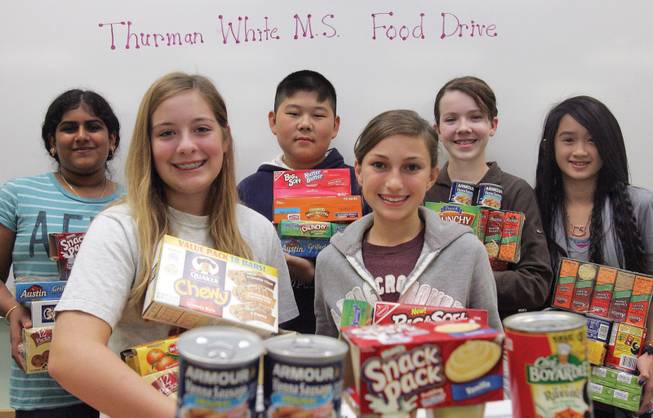 From left to right, members of the Thurman White Middle School student council and National Junior Honor Society Lakshmeeramya Malladi, Allessandra Brice, Anthony Ku, Lindy Eskin, Ariana Marciel and Linh Foschi hold armfuls of food collected for the holidays.