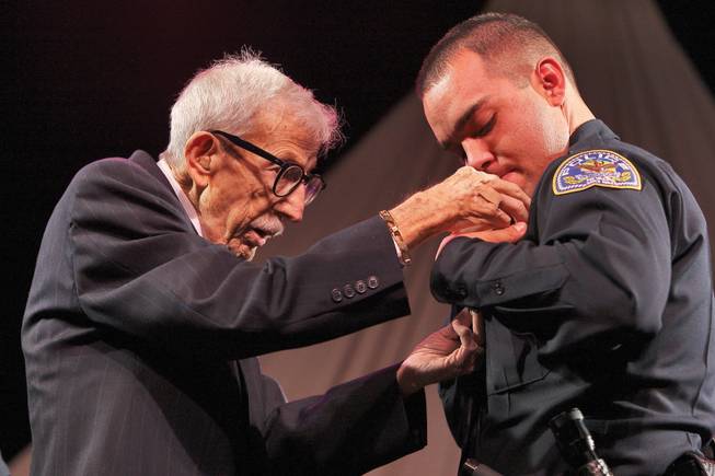 Following a family legacy of public service, Henderson Police officer Daniel Medrano receives his badge from his grandfather, retired Gillette, Wyo., police chief Lou Pappas, 84, at the Southern Desert Regional Police Academy commencement ceremony.