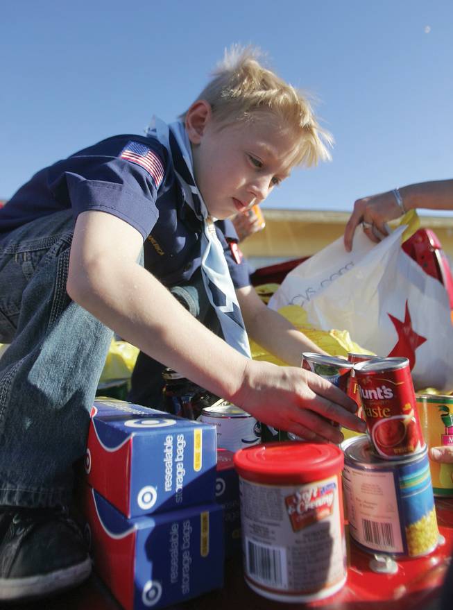 Christian Bozeman, from Pack 614, sorts canned foods as part of the Boy Scout holiday food drive at the Henderson Salvation Army on Saturday.