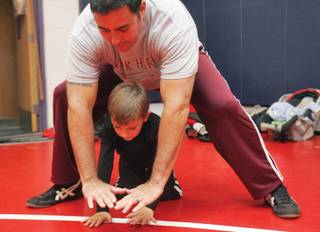 Coach Kalani Watanabe shows Quentin Reyes, 6, how to do a diamond push-up during Junior Patriots Wrestling Club practice at Liberty on Nov. 12. Expected to feed future high school athletes, the club is a youth program for elementary and middle school students around Liberty High School.    
