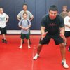 Coach Randy Martinez, right, shows young wrestlers proper stance positions during Junior Patriots Wrestling club practice at Liberty. Expected to feed future high school programs, the club is for elementary and middle schools students around Liberty.