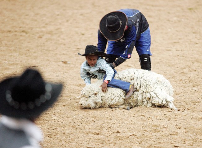 Jarvis Denery gets some help from Wayne Rogers after going head over heels while riding a sheep in a competition Saturday. The Pickett Rodeo has been around for a quarter-century, and this was its second appearance at South Point.