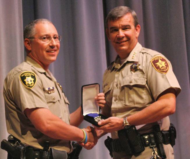 Sheriff Doug Gilespie, right, presents Detective Ethan Grimes with his medal for going above and beyond the call of duty.