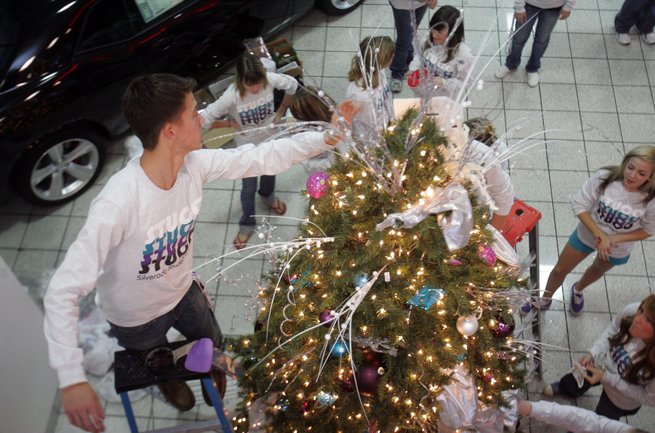 Ryan Cross, a senior at Silverado High School, helps put the final touches on a Christmas tree as Silverado competes in Valley Auto Mall's annual Christmas tree decorating contest at Towbin Dodge.  