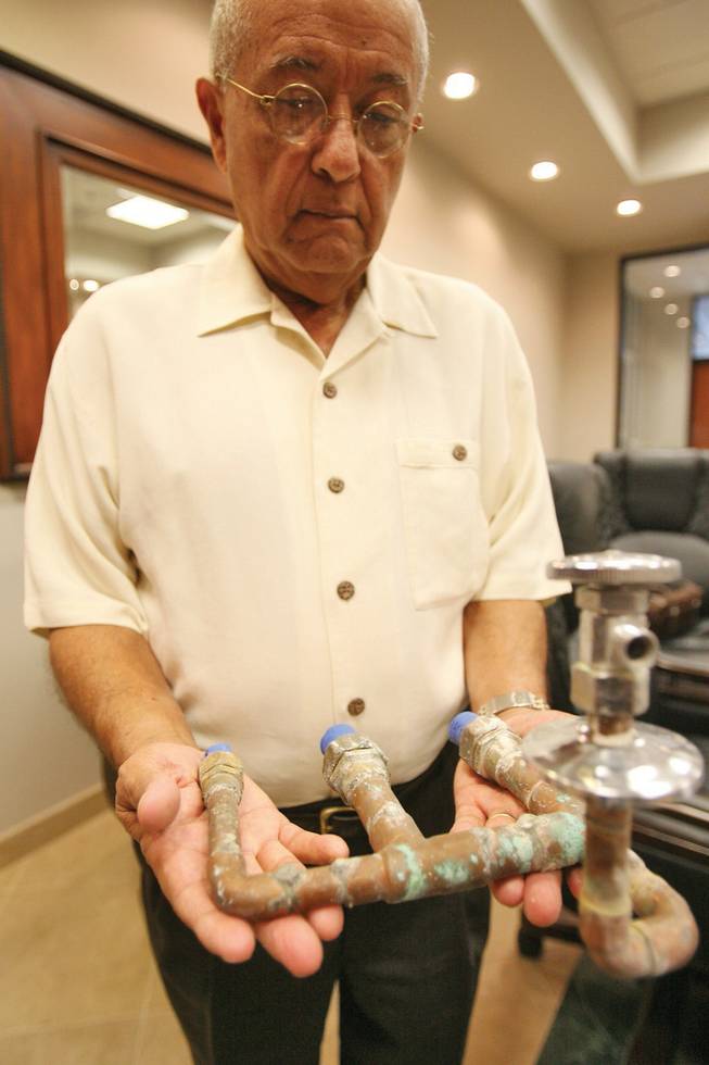Richard Garcia, in the office of his attorney, Neal Hyman, holds a faulty Ipex pipe fitting that was removed from one of his neighbor's homes.