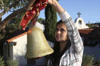 While placing the finishing touches around the grounds, Angela, 12, a St. Jude's Ranch resident, hangs a holiday bell from a tree Monday in preparation for the Night of Lights at Jude's Ranch for Children.