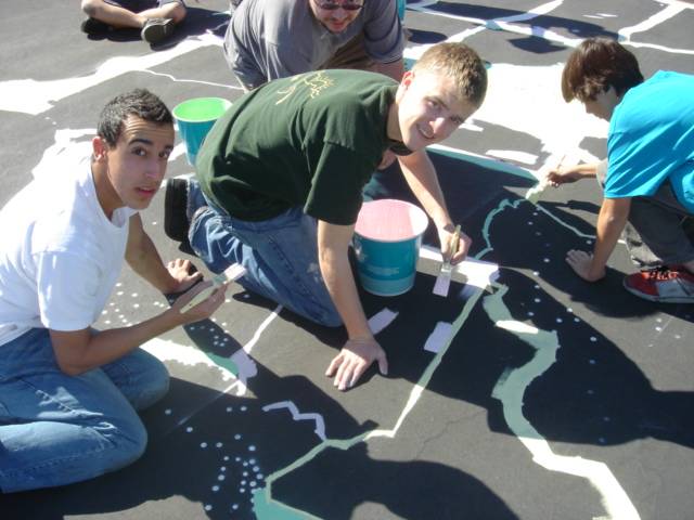 From left, Ofir Barashy, Trevor Scheer and Kerry Sandhu paint a mural of the United States on the blacktop at Eisenberg Elementary School.