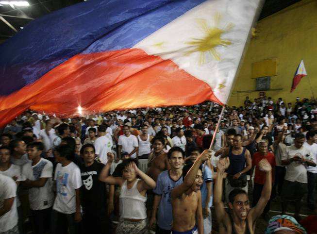 Filipinos wave a Philippine flag as they celebrate the victory of Filipino boxing icon Manny Pacquiao over Oscar De La Hoya while they watch it beamed live via satellite at the Tondo Sports Complex in Manila, Philippines on Sunday Dec. 7, 2008. From five-star hotel lounges and army camps to Manila's burgeoning slums, Filipinos gathered in huge numbers to cheer the country's boxing icon, as officials say the victory provided the country a momentary respite from financial worries.