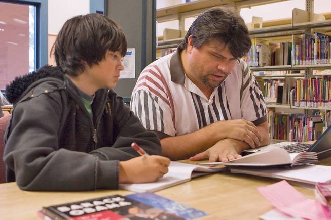 Bob Adamovich, right, assists his son Samual, 13, on writing a biography on President-elect Barack Obama at the Green Valley Library.