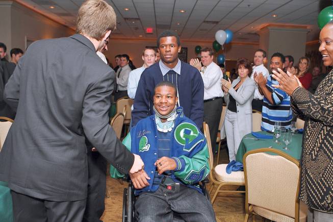 Green Valley High senior LaQuan Phillips, being pushed by teammate Derrick Stevens, heads to the podium during the Gators' football banquet to receive the team's "Go For Broke" award from the Home News on Dec. 4. The award honors high school football players for being a hard worker and an inspiration to teammates.