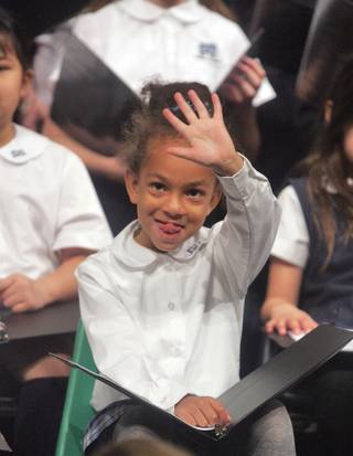 Nathalie Blackwell, age 5, waves to someone in the audience during Adelson Educational Campus choir's annual Hanukkah concert on Dec. 15.  