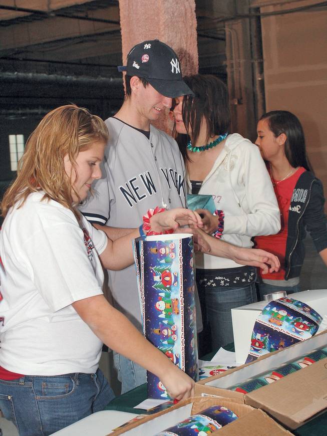 From left to right Tori Hedrick 14, Ross Niedermeir 17, and Laura Niedermeir 15, Coronado High School band students wrap gifts out at Town Square to help raise money for band events, including Honor Band in January.