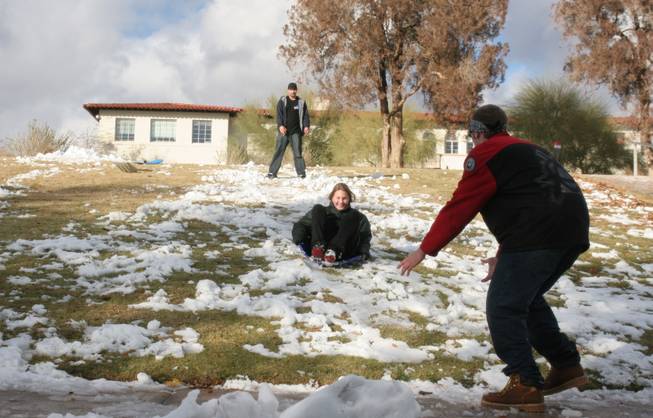 Dayna Pullen slides down the remaining snow on the Bureau of Reclamation's lawn in Boulder City today. Pushed by her brother, Tyler Pullen, and caught by her brother, Alex Martincek, Dayna was enjoying a day off from Elton Garrett Middle School. Clark County School District called a snow day for the first time since 1979.