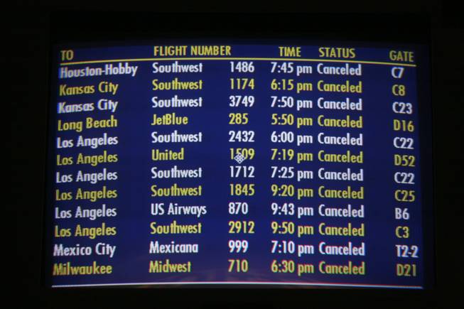 A video monitor displays cancelled departure flights at McCarran International Airport Wednesday.  A rare snowstorm blanketed the Las Vegas Valley, delaying flights, causing widespread fender-benders and leading to the cancellation of several events.