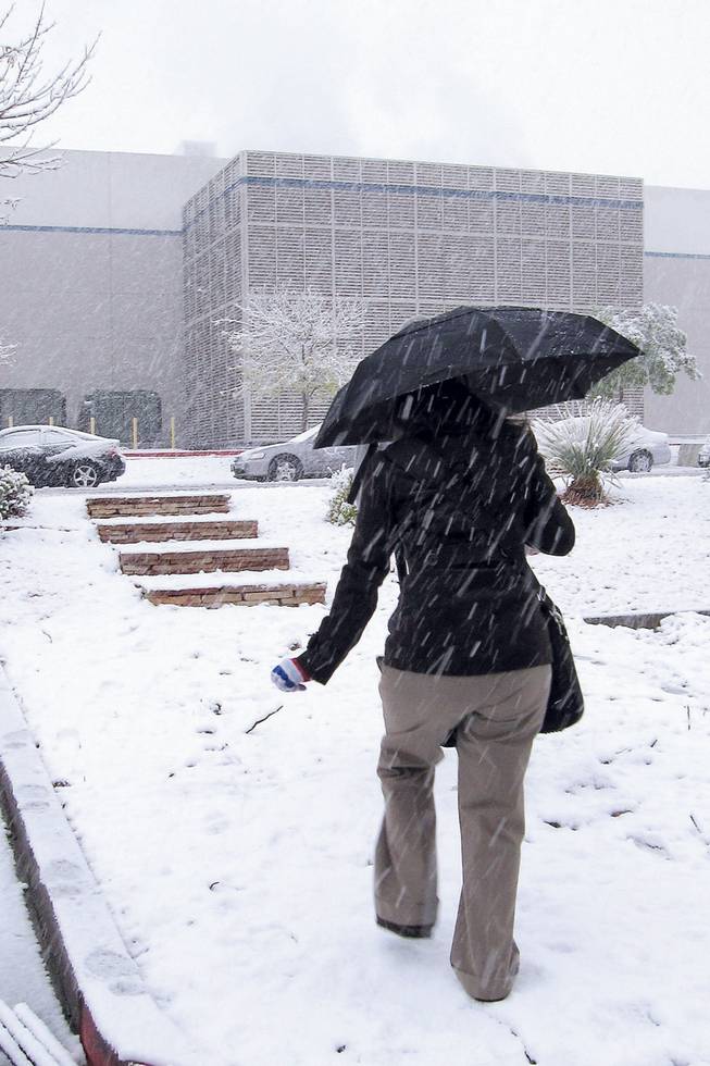 A student attempts to avoid the snow as she head towards her car after class from Touro University Nevada on Wednesday.