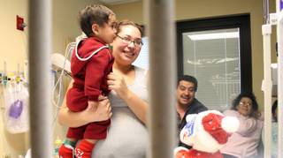 Shella Salazar and her son Angel Manuel Salazar receive gifts from highway patrol at Sunrise Children's Hospital Intensive Care Unity Wednesday.