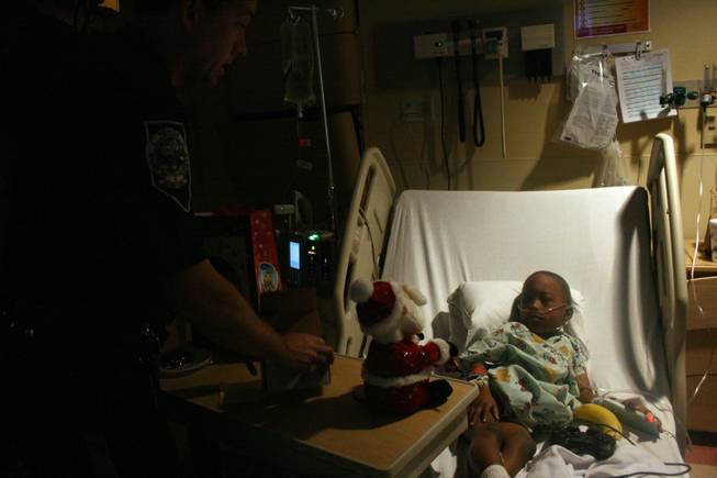 Daejon Meadows receives gifts from the Nevada Highway Patrolman Bobby Borchardt at Sunrise Children's Hopsital Intensive Care Unity Wednesday.