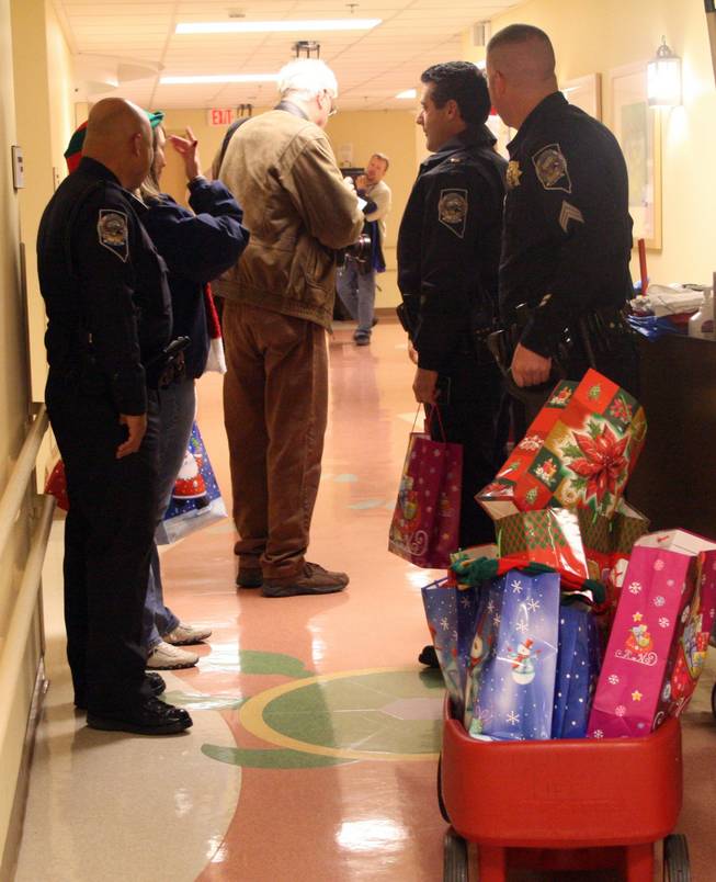 Highway patrolmen wait outside a patient's room with a wagon full of gifts to give to children in the Intensive Care Unit at Sunrise Children's Hospital Wednesday.