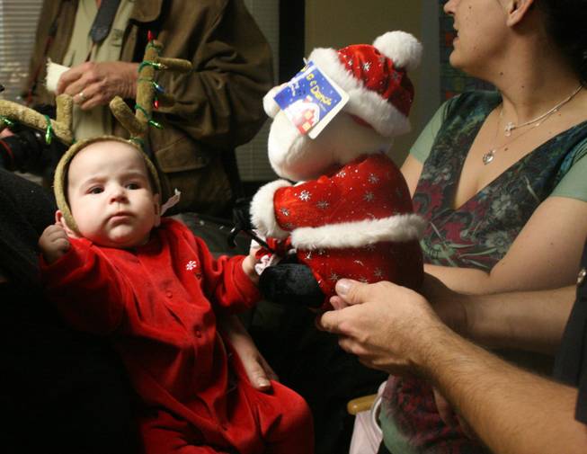 Danielle Peach, 5 1/2 months old, stares inquisitively at the singing and dancing Santa she just received from a member of the highway patrol Wednesday.