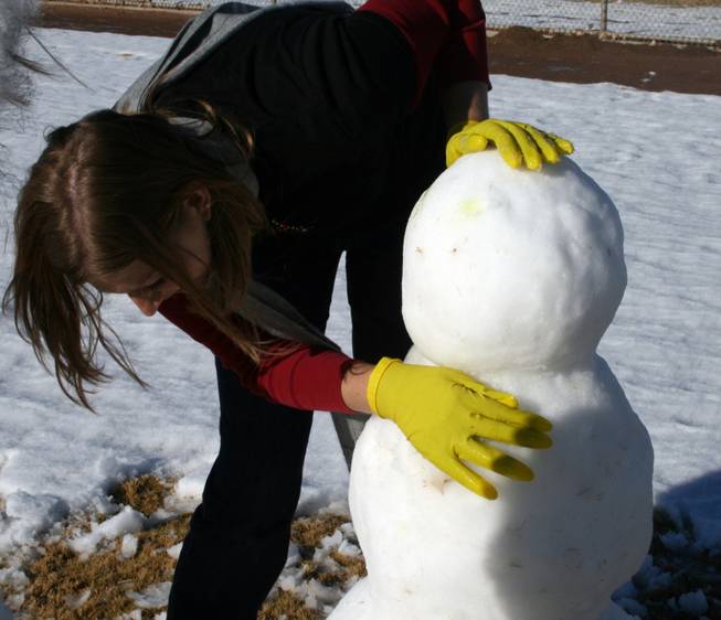 Gilbert Magnet School teacher Mary Elliot perfects the snowman she and her two sisters built at Sunset Park Thursday. They were joined by their mother who said her daughters wanted to get together and play in the snow, but there wasn't enough at her house.