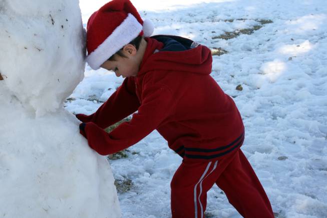 Levi Wright rests his head on the snowman he and his brothers built Thursday at Sunset Park at South Eastern Avenue and East Sunset Road.