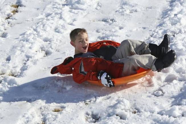 Taking advantage of his school's snow day, Nathan Winder, 8, twirls on his sled down the hills of Anthem Hills Park Thursday morning.