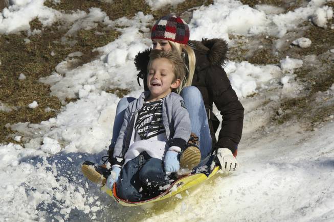 Toby Medina, 6, closes his eyes as he races down the snow-covered hills on his sled with Aspen Daley, 14, right, at Anthem Hills Park Thursday afternoon.