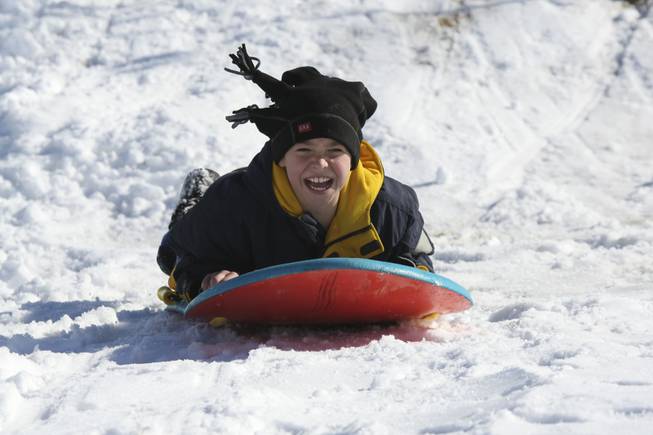 Ten-year-old Blake Forte smiles all the way down the snow-covered hills while sledding at Anthem Hills Park Thursday morning.