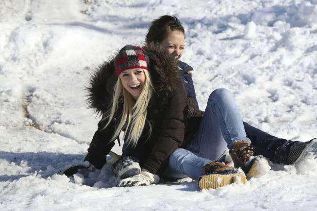 Friends Aspen Daley, 14, and Tori Medina, 14, laugh as they land hard at the bottom of the hill while sledding in Anthem Hills Park Thursday afternoon.
