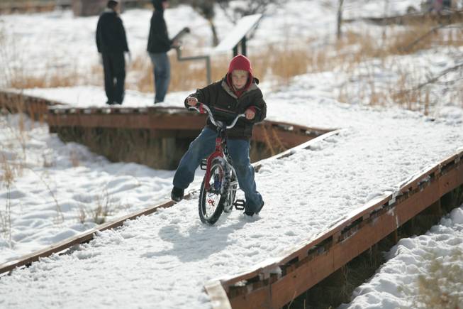 Ober Elementary School second grader Anthiony Urizi, 8, attempts to ride his bike on an icy walkway while playing in the snow at Red Springs in Red Rock Canyon National Conservation Area Thursday.