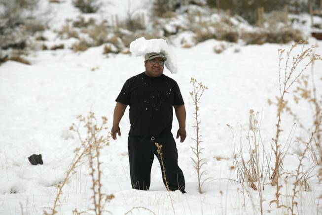 Javier Panca balances a piece of ice on his head while playing in the snow at Red Springs in Red Rock Canyon National Conservation Area Thursday.