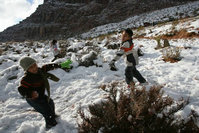 Adrian Moreno, 4, left, and Ulisses Diaz, 8, toss snow balls at each other while playing at Red Springs in Red Rock Canyon National Conservation Area Thursday.