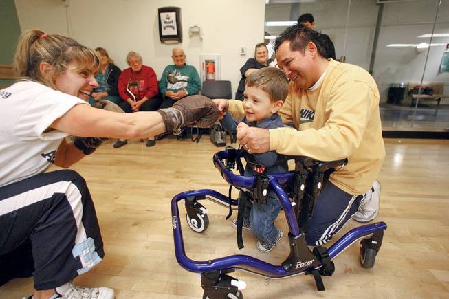 Linda Rossi, left, shadowboxes with her son Dominic, 2, as volunteer Sergio Tellez helps during the year's final Paralympic Academy event at the Henderson Multigenerational Center Dec. 10.