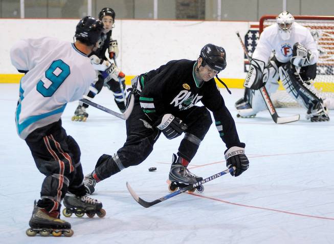 Leroy Garcia, left, whips a pass through the legs of Rob Wilson (center) to a teammate during a Las Vegas Aces team practice at the Las Vegas Roller Hockey Cener on Dec. 14. At right is netminder Darrel Kinnear closely watching the play.