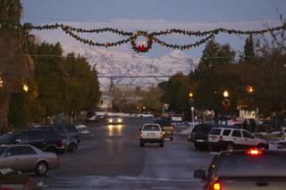 Holiday garland and lights hung across Arizona Street twinkle in the evening sky as the snowcapped mountains fade into the distance as the sun sets in Boulder City.