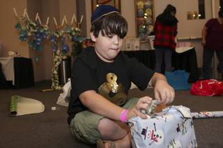Andrew Stafford, 10, concentrates while taping a present he wrapped during the wrap-a-thon for the adopt-a-family project at Midbar Kodesh Temple Dec. 16.