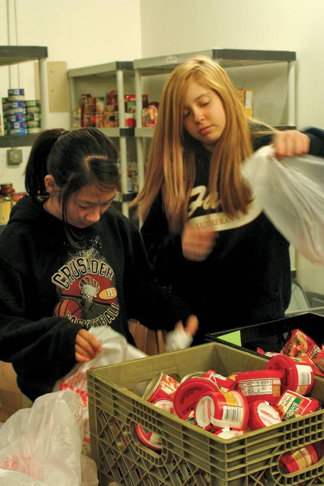 Bri Wii, 12, left, and Carli Olden, 12, place items in bags and pass them down the assembly line at the Caring 4 Kids Foundation on Dec. 19. The Faith Lutheran students were participating in the school's annual service day.