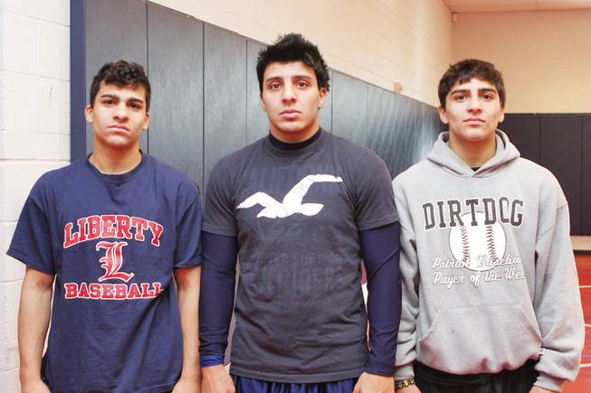 Anthony Reveles, center, coaches brothers, Mike Reveles, left, and Rudy Reveles, right, on Liberty's wrestling team. Anthony, 20, was a state qualifier for hte Patriots during his career at the school.