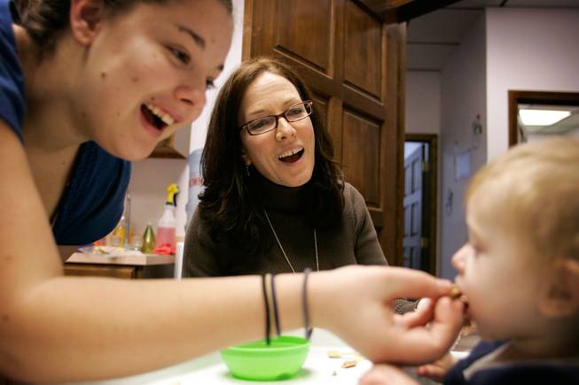 Therapist Julie Cole, center, and mother Drew Belk, left, help 13-month-old Emma Belk learn to eat during feeding therapy at Cole's office in Las Vegas on Tuesday, Dec. 30, 2008. Belk, who has Medicaid insurance, has been in feeding therapy since November 2008 and has made a lot of progress, though Cole fears she may have to stop taking Medicaid patients because the reimbursement rate has been cut in Nevada. 