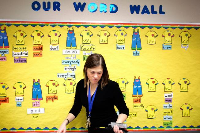 Kerri Soper, who teaches third grade at Bob Forbus Elementary School, puts more words on her word wall while readying the classroom for her students to return from track break Friday, Jan. 9, 2009. Soper struggles to pay her bills and says a 6% pay cut would be a financial burden. 
