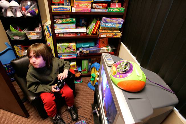 Cory Steelsmith, 11, plays a video game while waiting for his therapist at Henderson Speech Hearing and Language Center on Wednesday, Dec. 24, 2008. Cory has had three open heart surgeries, and during the first he suffered brain damage that affected his speech, motor skills and socialization. Henderson Speech, Hearing and Language Center's Elissa Mandel, a speech-language pathologist, is seeing Cory pro bono. 