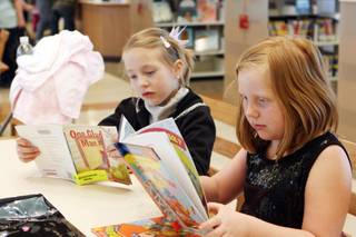 Taylor Simmons, 7, left and Chloe Atwell, 7 read books Saturday at the opening of the Centennial Hills Library.