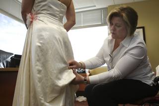 Sewing instructor Carol Franklin marks the gather point on the train of U.S. Army Capt. Riane Nelson's wedding dress. The dress was designed as a benefit to soldiers by International Academy of Design & Technology senior Teresa Lastowski.